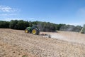 John Deere tractor ploughing a field with a disc harrow in summer Royalty Free Stock Photo