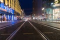 Friedrichstrasse retail shops line both sides of street with lights reflecting of tram lines