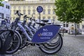 Parked rentable bikes in downtown Berlin, Germany, with the unfocussed town castle in the background