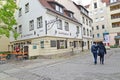 BERLIN, GERMANY. Rare bystanders walk past the Zum Nusbaum beer bar. German text