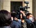 Reporter with a small video camera films from a distance policemen with white face coverings at the Anticorona demonstration