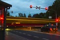 Long exposure of a night scene from a railroad crossing with red warning lights and rays of light from a passing train in Berlin