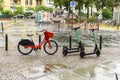 Parked rental bicycles and rental scooters on a square in downtown Berlin on a rainy day