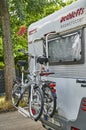 A parked white motorhome with a cycle carrier attached to the rear, with two bicycles