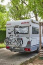 A parked white motorhome with a cycle carrier attached to the rear, with two bicycles