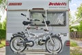 A parked white motorhome with a cycle carrier attached to the rear, with two bicycles