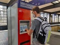 A young caucasian traveler is buying a railway ticket in red vending machine Royalty Free Stock Photo