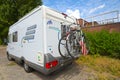 A white motorhome with a cycle carrier attached to the rear, with two bicycles