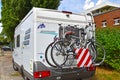 A white motorhome with a cycle carrier attached to the rear, with two bicycles