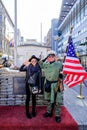 Unidentified young woman and men dressed as American soldiers stand near the checkpoint Charlie.