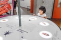 Asian Child girl using interactive touch screen, to know about insects voices in a museum