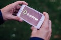 BERLIN, GERMANY - MAY 30, 2018: Closeup of hands holding iPhone screen with GUMTREE LOGO and ICON