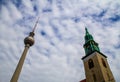 Berlin, Germany - May 31, 2019: Fernsehturm and church tower reaching for the fluffy clouds with blue sky above the city Royalty Free Stock Photo