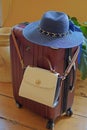 Ready to travel! A suitcase, on which a sun hat lies and at which a lady`s handbag is hung