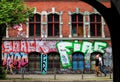 Berlin, Germany - May 14, 2014: side view street with a brick wall full of graffiti and some people walking