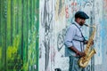 Berlin, Germany - May 14, 2014: street artist plays a sax in front of the Berlin Wall, East Side Gallery, Berlin, Germany Royalty Free Stock Photo