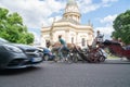 Traditional style building with brass dome and gold statue with three modes of transport blurred in motion passing on street