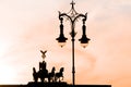 Berlin, Silhouette of Quadriga on Brandenburg Gate and nostaligic street lamp in backlight in orange evening sky at sunset