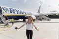 08 21 2018 - Berlin Tegel, Germany: Beautiful young woman with passport standing and smiling in front of Ryanair airplane on