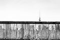 Berlin Wall original weathered section damaged with exposed iron bars partly covering the TV tower Berliner Fernsehturm