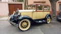 Old cream 1930s Ford Model A Fordor sedan three window parked in the street. Classic car show.