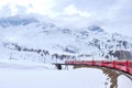 Bernina mountain pass. The famous red train is crossing the white lake. Amazing landscape of the Switzerland land. Famous