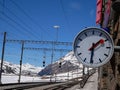 Berninna Express clock train station in the middle of swiss mountains in winter - wide panorama