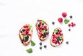 Berries bruschetta on a light background, top view. Sandwiches with cream cheese, raspberries, red and black currants. Delicious b