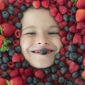 Berries child face close up. Top view photo of child face with berri. Berry set near kids face. Cute little boy eats Royalty Free Stock Photo