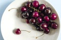 Berries of freshly washed dark cherries on a light plate close-up.