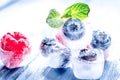 Berries frozen in ice cubes with mint on wooden table background Royalty Free Stock Photo