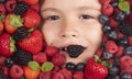 Berries with kids face close-up. Top view of child face with berri. Berry set near kids face. Cute little boy eats Royalty Free Stock Photo