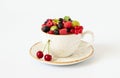 Berries in a mug on a white background. Cherries, raspberries, gooseberries and red currants in a cup. Juicy fresh berries Royalty Free Stock Photo