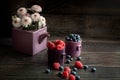 Berries raspberries and blueberries in a cup on a wooden table. Chrysanthemums in the teapot. Still life. Place for your