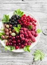 Berries - raspberries, gooseberries, red currants, cherries, black currants on a white plate Royalty Free Stock Photo