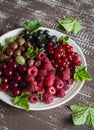 Berries - raspberries, gooseberries, red currants, cherries, black currants on a white plate