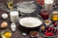 Berries, sifted flour in black plate, cocoa powder. Measuring cup with flour, glass of milk, broken egg and salt, metal whisk Royalty Free Stock Photo