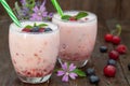Berries smoothies in two glasses with straws on wooden table Royalty Free Stock Photo