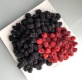 Berries on a white plate, raspberries and blackberries. Royalty Free Stock Photo