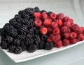 Berries on a white plate, raspberries and blackberries. Royalty Free Stock Photo