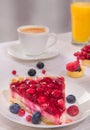 Berry cake on a plate multiple fresh berries on table glass of orange juice and white cup of coffee Royalty Free Stock Photo