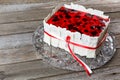 Berry cake with red jelly knotted red and white tape on a glass dish. Wooden background