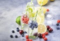 Berry and citrus fruit infused summer cold drinks in glass bottles on gray stone table background, copy space Royalty Free Stock Photo