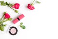 Berry color decorative cosmetics with roses white background top view