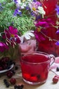 Berry compote in a glass cup, berries and a bouquet of wild flowers on a deoanean background. Rustic style.