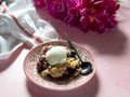 Berry crumble with ice cream on plate. Pink background with lilac peonies. Copy space. Closse up