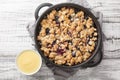 Berry fruit crumble baked with apples and blueberries served with vanilla sauce close-up in a pan. Horizontal top view