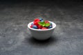 Berry fruit with waterdrops in white ceramic bowl on dark concrete background. Royalty Free Stock Photo