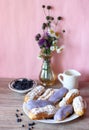 Berry glazed eclairs with blueberries on a wooden background with a decor consisting of a vase with wildflowers and a Royalty Free Stock Photo