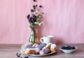 Berry glazed eclairs with blueberries on a wooden background with a decor consisting of a vase with wildflowers and a Royalty Free Stock Photo